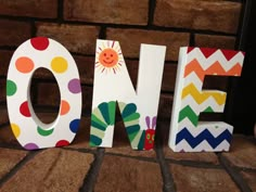 the word one is made out of wood and decorated with multicolored polka dots