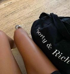 a person sitting on the floor next to a bag with writing on it and their legs crossed