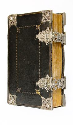 an old black leather book with gold trimmings on the edges and sides, open