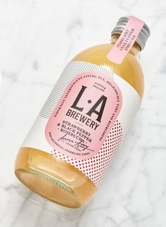 a bottle of la brewery sitting on top of a white marble countertop next to a pink label