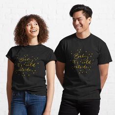 two people wearing black t - shirts with gold foil lettering on the front and back