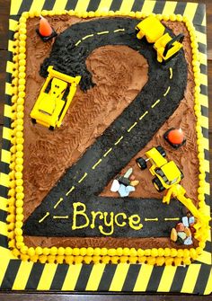 a birthday cake for a two year old boy with construction vehicles on the road and number 2