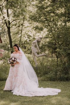 a woman in a wedding dress standing next to a statue