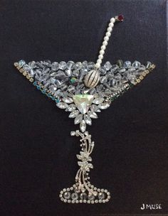 an elaborately decorated martini glass with pearls and jewels on it's side, in a black frame