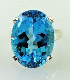 ALL OUR GEMSTONES ARE NATURAL NOT LAB CREATED ALL OUR JEWELRY IS HANDCRAFTED IN THE U.S.A. BIG, brilliant and intensely blue  This chunky, natural gem is over 21 carats of genuine Top Swiss Blue Topaz set in a classic mounting that's all about showing off this incredible stone.  Guaranteed to be an eye-catcher!  Whether for yourself or a loved one who loves flashy gems, this ring makes a BOLD statement and will certainly get noticed!  The setting can be made of solid .925 sterling silver, 10kt, Turquoise Oval Topaz Ring, Oval Turquoise Topaz Ring, Swiss Blue Topaz Ring, Aquamarine Colour, Swiss Blue Topaz, London Blue Topaz, Blue Topaz Ring, Topaz Gemstone, Topaz Ring