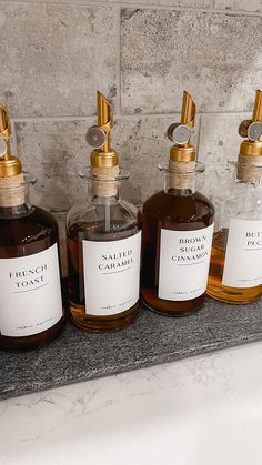 three bottles of brown liquid sitting on top of a counter next to a bath tub