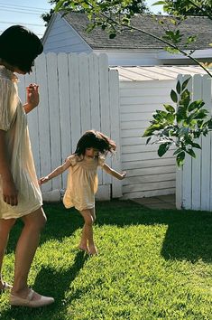 a woman and child are playing in the grass