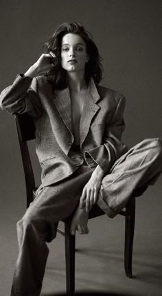 a black and white photo of a woman sitting in a chair with her hand on her head