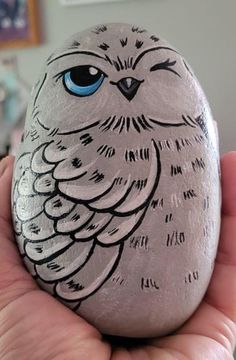 a hand holding a rock with an owl painted on it