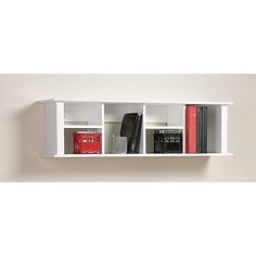 a white book shelf with books on top of it and two red boxes in the middle