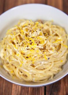 a white bowl filled with pasta on top of a wooden table