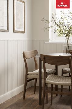 a dining room table with two chairs and a vase on the table next to it