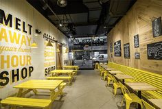 the inside of a shop with yellow benches and chalkboard on the wall behind them