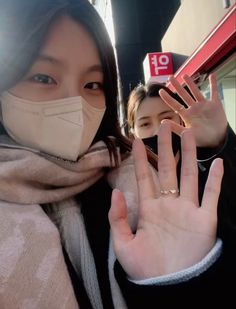 a woman wearing a face mask and making the v sign with her hand in front of her