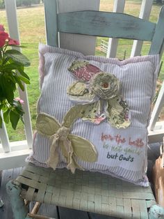 a chair with a pillow on top of it next to a potted plant and some flowers