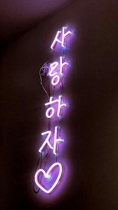 a neon sign that says i love you in english and korean letters are lit up against a dark background