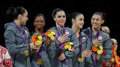 a group of women standing next to each other with medals around their necks and hands