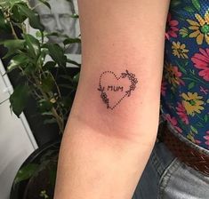 a woman's arm with a heart shaped tattoo on the left side of her arm