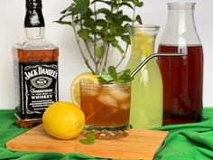 three different types of drinks sitting on a table next to bottles and a cutting board