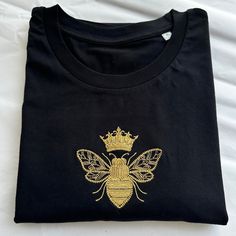 Embroidered Queen Bee T-shirt using a lovely soft t-shirt! This little design is embroidered by me, it's a super cute basic Tee and would make a great gift for someone special or little treat to yourself! The t-shirts are unisex so have a relaxed fit for ladies. *Eco-Friendly tee from a sustainable and ethical wholesaler* I am a size 12/14 and like to wear a large. Each item is made to order so if you need further measurements please send me a message. Machine Embroidered Short Sleeve T-shirt As Gift, Machine Embroidered Short Sleeve T-shirt For Gift, Embroidered Short Sleeve T-shirt For Gift, Casual T-shirt With Machine Embroidery As Gift, Crew Neck Tops With Machine Embroidery For Gifts, Casual T-shirt With Machine Embroidery For Gift, Casual T-shirt With Embroidery As Gift, Embroidered Crew Neck T-shirt Gift, Cotton T-shirt With Letter Embroidery As Gift