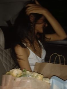 a woman sitting in the back seat of a car holding a paper bag