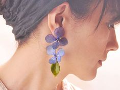 a close up of a person wearing earrings with blue flowers on the back of their ear