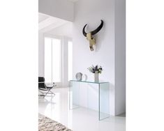 an animal skull mounted on the wall next to a glass table with flowers in it