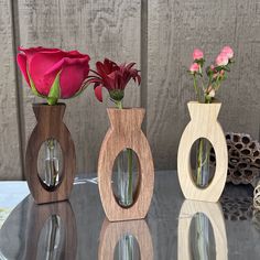 three wooden vases with flowers in them on a table