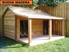 a dog house built into the side of a fenced in area with grass and trees