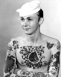 an old black and white photo of a man with tattoos on his chest wearing a sailor's hat