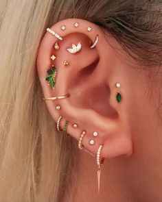 a woman's ear is adorned with different types of piercings and jewelry pieces