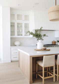 a kitchen island with two chairs and a potted plant on it in the center