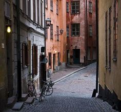 an alleyway between two buildings with bicycles parked on the side