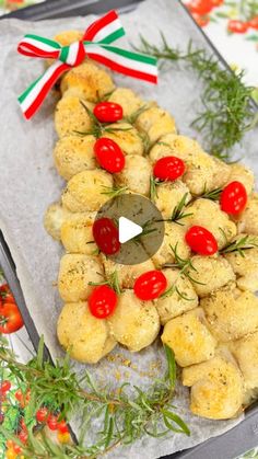 a christmas tree made out of doughnuts with tomatoes and herbs on top, sitting on a baking sheet