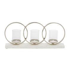 three glass candle holders sitting on top of a white countertop next to each other