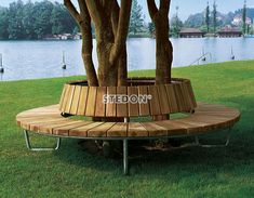 a wooden bench sitting on top of a lush green field next to a tree filled lake