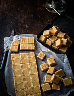 pieces of tofu sitting on top of a baking sheet next to a knife and bowl