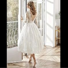 a woman in a white wedding dress looking out the window with her hand on her hip