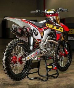 a red and white dirt bike sitting on top of a stand