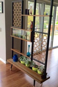 a shelf filled with pots and plants on top of a hard wood floor