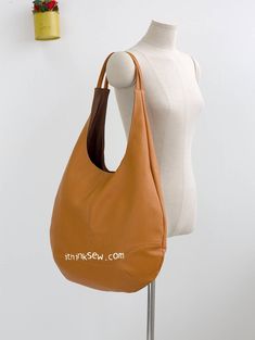 a mannequin holding a brown purse next to a white wall