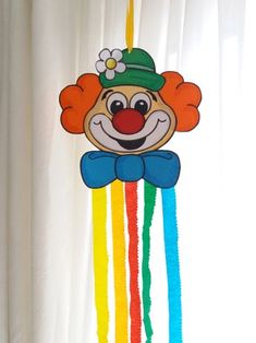 a colorful kite with a clown face hanging from it's side on a window sill