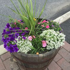 a wooden barrel filled with purple and white flowers