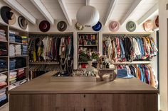 the closet is filled with many different types of clothes and hats on display in it