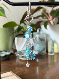 a close up of a key chain on a table with flowers and beads hanging from it