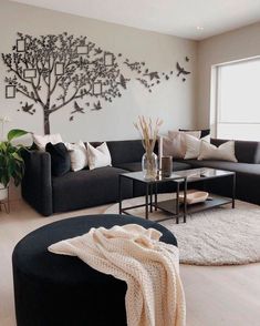 a living room filled with furniture and a large tree on the wall above the couch