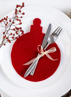 a white plate topped with a knife and fork next to a red felt ornament