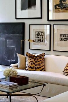 a living room filled with furniture and framed pictures on the wall above it's coffee table