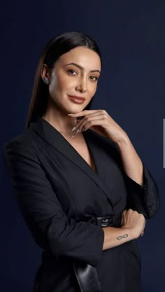 a woman posing for the camera with her hand on her chin and wearing a black jacket