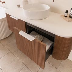 a white sink sitting next to a wooden cabinet